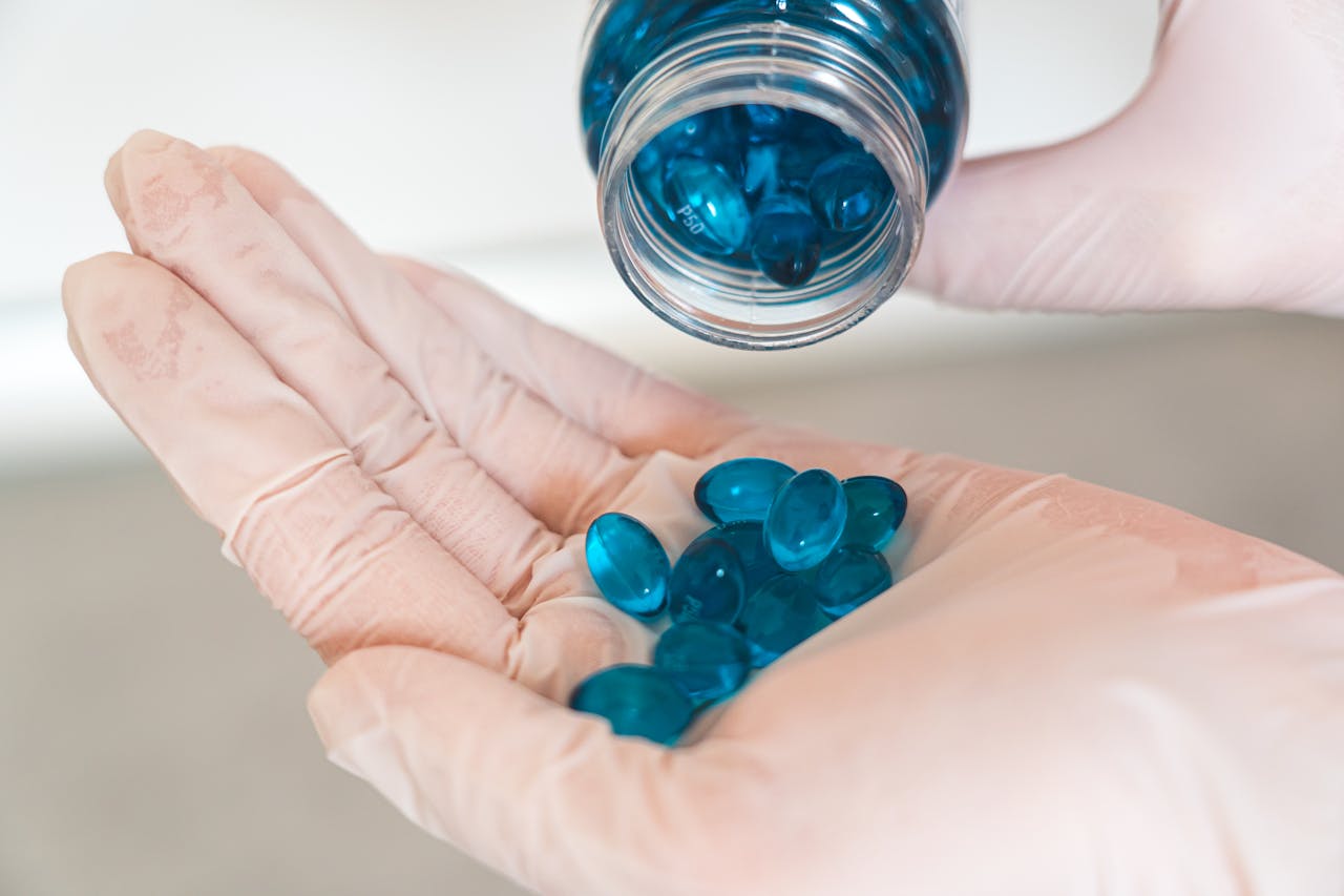 service-06 Close-up image of a healthcare worker with latex gloves pouring blue capsules from a bottle.